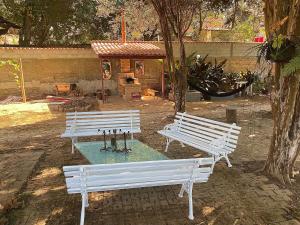 two white benches in a park with a fountain at Casa de Nara in São João del Rei