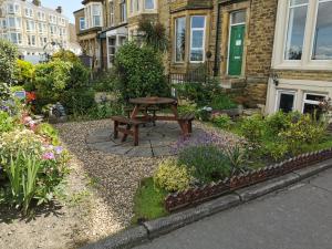 a garden with a wooden table in front of a building at Westleigh B&B in Morecambe