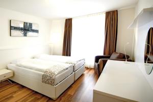 una camera bianca con un letto e una sedia di Luxury Apartments by Livingdowntown a Zurigo