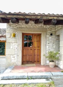 una puerta de madera de una casa de piedra con una maceta en LA SOLANILLA -Casas Rurales, en Torre Val de San Pedro