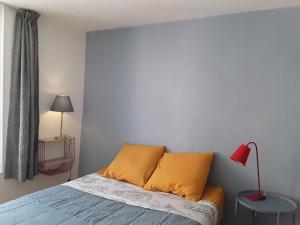 1 dormitorio con 1 cama con almohadas amarillas y lámpara roja en Le Velo Rouge, en Le Puy en Velay