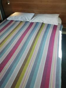 Una cama con una manta de rayas multicolor. en SUN1 SOUTHGATE, en Johannesburgo