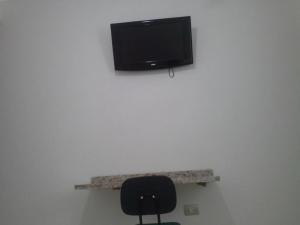 a room with a chair and a tv on a wall at Hotel Joabi in São José dos Campos