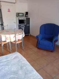 een woonkamer met een tafel en een blauwe stoel bij Studio plain-pied in Montjaux