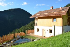 a house on the side of a hill with a pond at Naturchalet in San Vigilio Di Marebbe