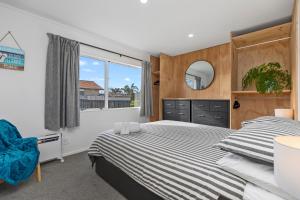 a bedroom with a bed and a large window at Lazy Sun Daze - Papamoa Holiday Home in Papamoa