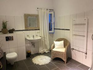 uma casa de banho com um lavatório, um WC e uma cadeira. em Im Herzen Bayerns em Töging am Inn