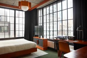 a bedroom with a bed and a desk and windows at Ace Hotel Brooklyn in Brooklyn