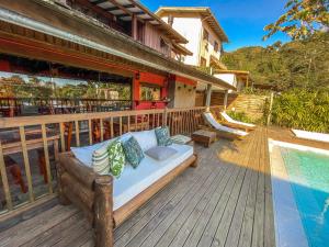 a wooden deck with a couch and a swimming pool at Morada da Praia do Rosa Pousada in Praia do Rosa