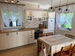 a kitchen with a table and a kitchen with white cabinets at Erika Apartmanház in Dombóvár