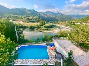 a swimming pool with a view of a river and mountains at Neretva River Guesthouse in Konjic