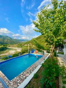 a swimming pool with a tree next to a river at Neretva River Guesthouse in Konjic