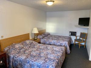 a hotel room with two beds and a chair at Hitching Post Motel in North Battleford