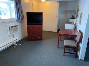 a room with a desk and a television and a table at Hitching Post Motel in North Battleford
