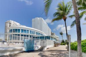 a building on the beach with a palm tree at Castle Beach: Serenity Condo in Miami Beach
