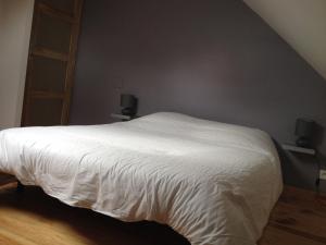 Un dormitorio con una cama con sábanas blancas. en OG Gîte, en Le Minihic-sur-Rance