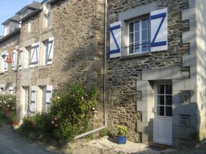 OG Gîte في Le Minihic-sur-Rance: مبنى من الطوب مع باب أبيض ونوافذ