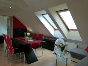 - un salon avec une table, des chaises rouges et des lucarnes dans l'établissement Apartament BB koło Cerkwi, à Krynica-Zdrój