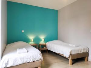 Duas camas num quarto com uma parede azul em Le Puy Carmin - Gîte 6 personnes - 18 min du PuyDuFou em Bazoges-en-Paillers