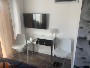 2 weiße Stühle und ein Schreibtisch mit einem TV an der Wand in der Unterkunft VILLA PERLA SAINT-TROPEZ CAVALAIRE sur MER, 3-5 chambres, vue mer, piscine chauffée avril à octobre in Cavalaire-sur-Mer