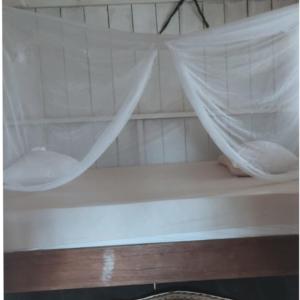 a white bed with a mosquito net in a room at Hospedaje KOWAPANA BOCAS DE AMACAYACU in Morelia