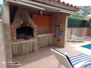 cocina con chimenea de ladrillo junto a la piscina en Villa descanso, en Alcanar