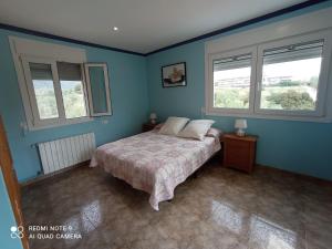1 dormitorio con 1 cama con paredes y ventanas azules en Villa descanso, en Alcanar