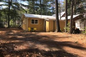 a small yellow house in the woods at Riverfront Rustic Cottage in Durham Bridge