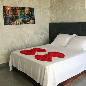 Una cama con dos toallas rojas encima. en Vilamar en Tibau do Sul