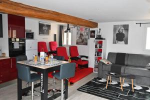 een woonkamer met een tafel en rode stoelen bij CINEMA Appartement 10mn Aeroport Roissy CDG in Villeneuve-sous-Dammartin