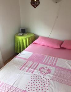 ein Bett mit rosa und weißer Bettwäsche und einem grünen Tisch in der Unterkunft Holiday House Crik in Crikvenica