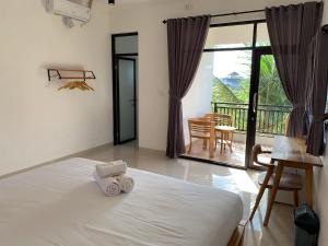 1 dormitorio con cama blanca y balcón en Kenan Cottage, en Canggu