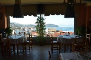 a restaurant with tables and chairs and a large window at Bahia de Chapela in Redondela