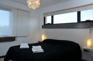 una camera da letto con un letto nero con due asciugamani di Dock Playa a Villa Gesell Altre 20 foto