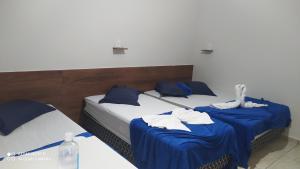 2 camas en una habitación de color azul y blanco en Pousada Quarto com frigobar,ar e garagem gratuita, en Aparecida