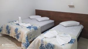 two beds in a hotel room with towels on them at Pousada Quarto com tv,ar,frigobar,wifi e garagem in Aparecida