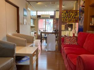 a living room with a red couch and a table at Guesthouse Namaste in Kanazawa