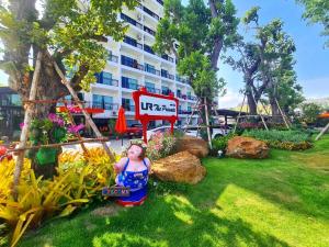 Una bambola seduta nell'erba vicino a un edificio di UR The Private Huahin a Hua Hin