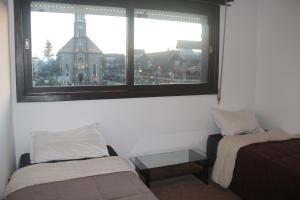 a room with two beds and a view of a building at Mais Incrível Localização de Gramado in Gramado