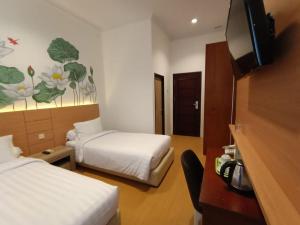 a hotel room with two beds and a television at Front One Green Boutique Hotel Abepura in Abepura