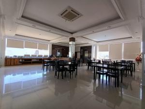 a dining room with black chairs and tables and windows at Front One Green Boutique Hotel Abepura in Abepura