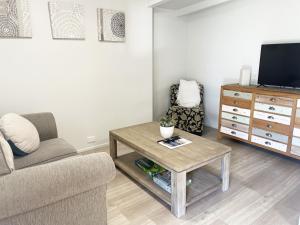 a living room with a couch and a table and a tv at Bribie Beach Bungalow in Bongaree
