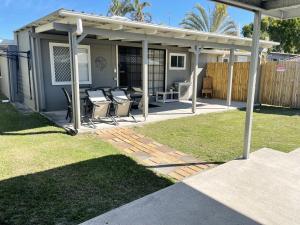 a patio with chairs and a pavilion in a yard at Bribie Beach Bungalow in Bongaree
