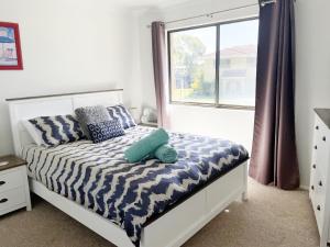 a bedroom with a bed with blue pillows and a window at Cloud 8 on Welsby in Bongaree