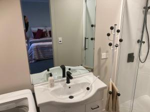 a white bathroom with a sink and a shower at Cambridge Te Awa Rivertrail BnB in Cambridge