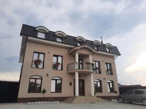a large white house with a black roof at AristoCat Hotels Rasnov in Râşnov