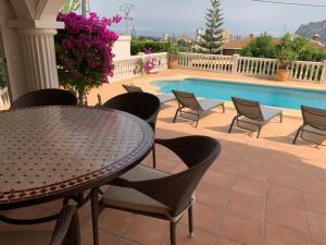 un patio con mesa y sillas junto a una piscina en THE BEST HOLIDAY VILLA, en Calpe