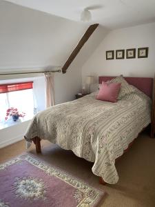 a bedroom with a bed with a pink pillow and a window at Splatthayes in Buckerell +37 photos