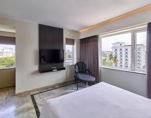特里凡得琅Ariya Nivaas A Vegetarian Hotel的一间配有床和平板电视的酒店房间