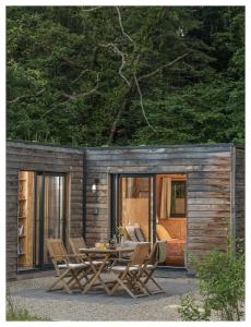 Cabaña de madera pequeña con mesa y sillas en Volvic Organic Resort, en Volvic